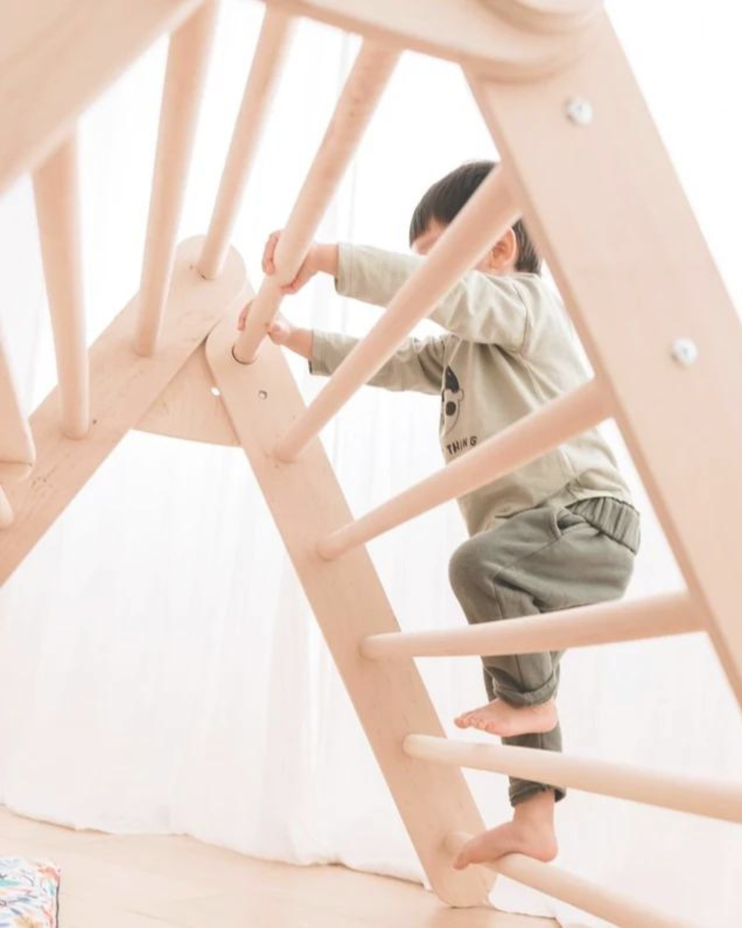 Enfant grimpant sur une structure en bois Montessori à la MAM Passerelle