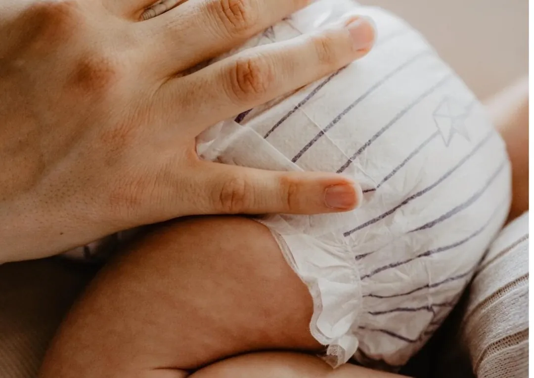 Bébé portant une couche saine, blottit contre un parent